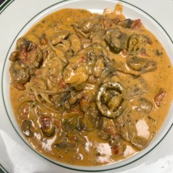 A plate of Roma Ristorante Italiano's creamy pasta with mushrooms and tomatoes.