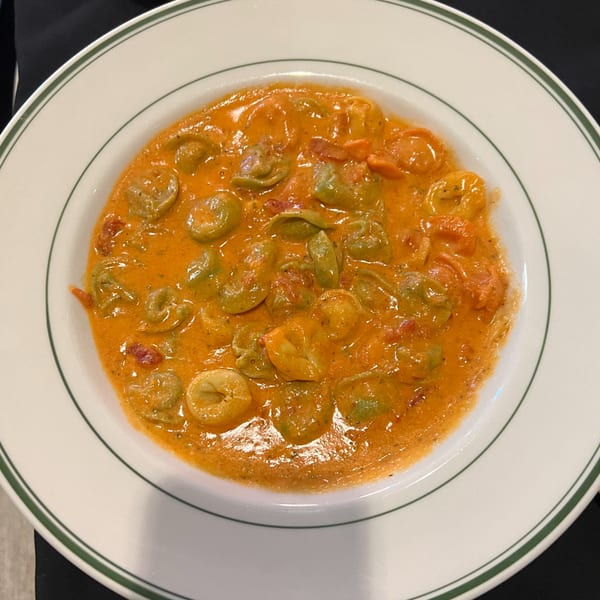 Roma Ristorante Italiano's tortellini pasta in a creamy tomato sauce, served in a white bowl.