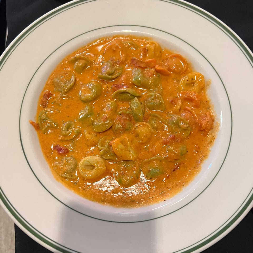 Roma Ristorante Italiano's tortellini pasta in a creamy tomato sauce, served in a white bowl.