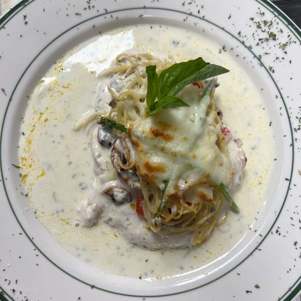 Creamy spaghetti with melted cheese, mushrooms, asparagus, and basil on a white plate.
