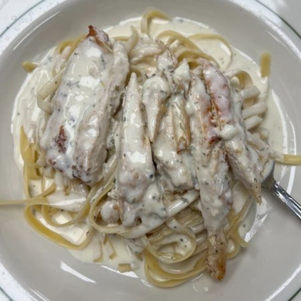Creamy chicken alfredo pasta with fettuccine noodles and a fork on a white plate.